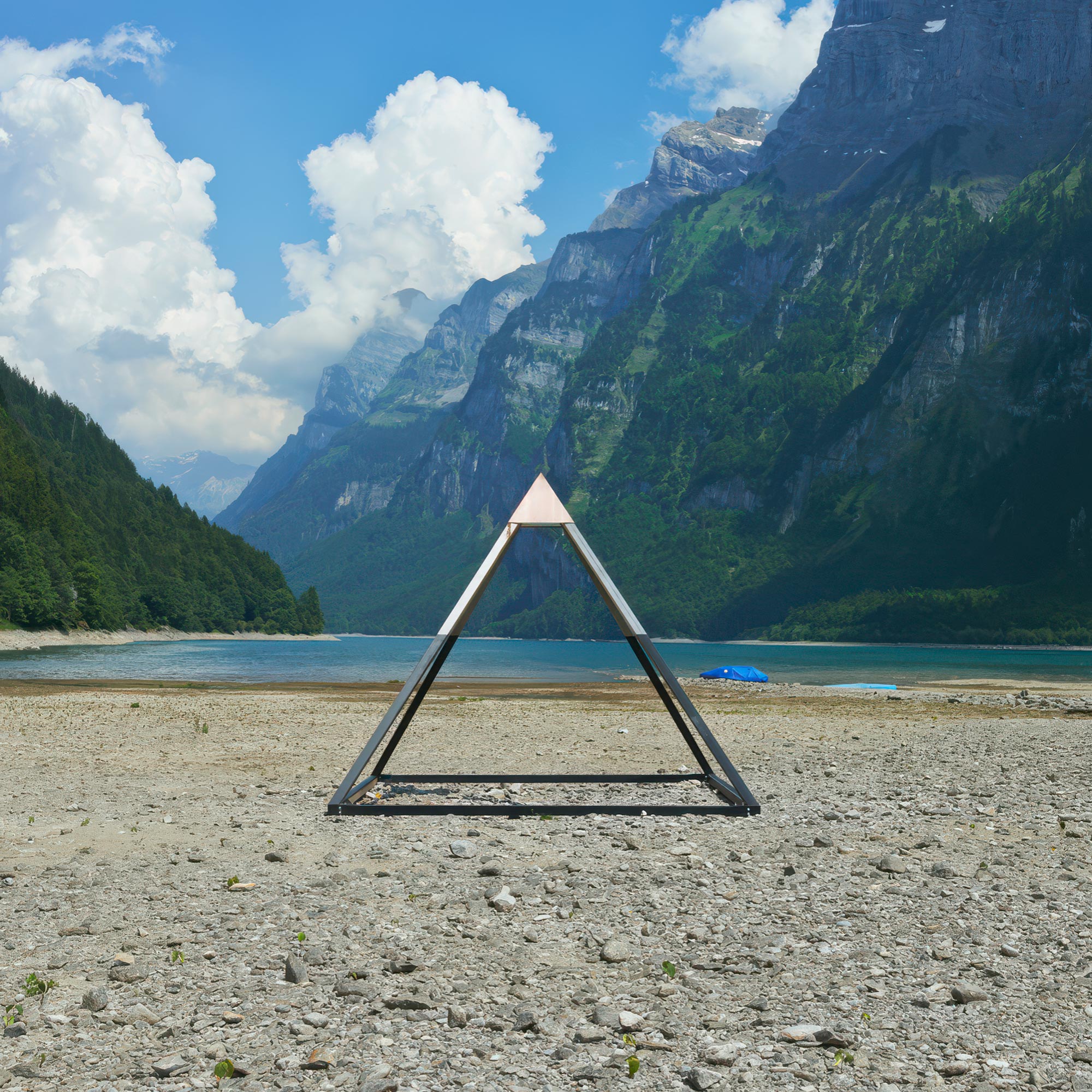 A pyramid shaped metal sculpture standing on the bottom of a half empty lake.